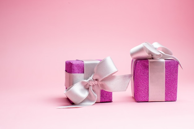 Vista frontale piccoli regali di natale su foto regalo di colore rosa di natale vacanze di capodanno
