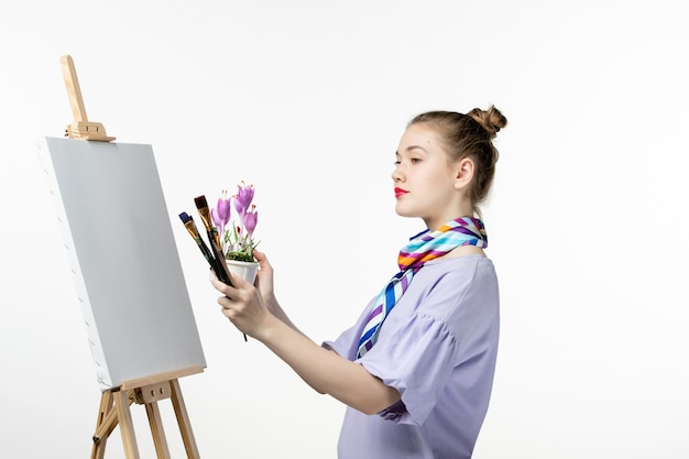 Vista frontale pittrice disegno immagine di fiore su un muro bianco disegnare artista cavalletto matita arte pittura donna