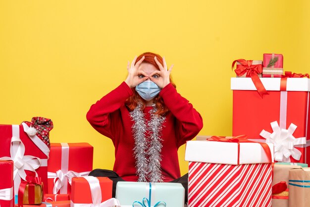 Vista frontale piuttosto femminile seduto intorno presenta in maschera su giallo