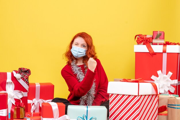 Vista frontale piuttosto femminile seduto intorno presenta in maschera su giallo