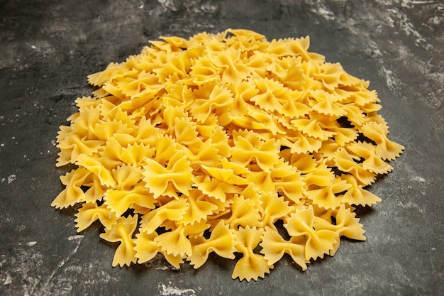 Vista frontale poca pasta cruda su cibo grigio scuro foto a colori molti pasta italiana pasta