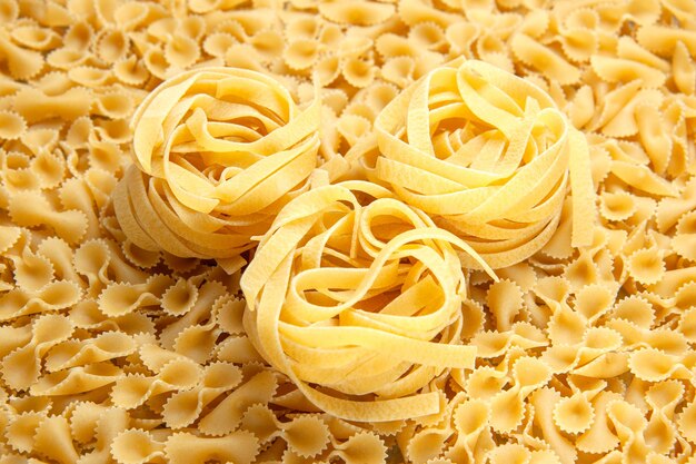 Vista frontale poca pasta cruda su cibo leggero con foto a colori di molti pasti di pasta