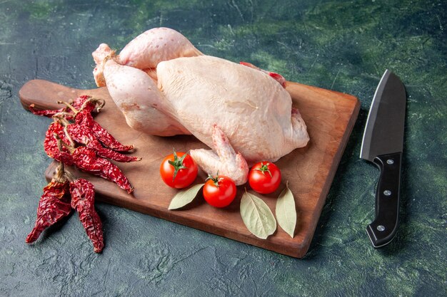 Vista frontale pollo crudo fresco con pomodori su cucina blu scuro ristorante pasto foto animale fattoria cibo carne di pollo colore