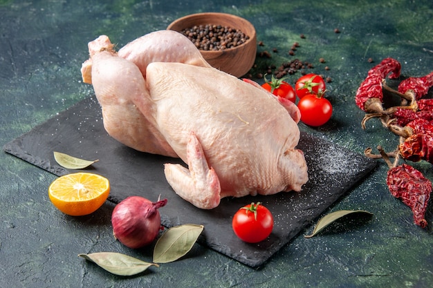 Vista frontale pollo crudo fresco con pomodori su farina scura foto animale colore alimentare pollo carne da cucina