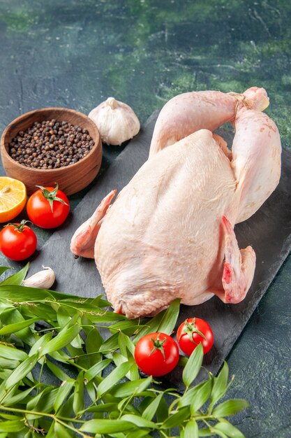 Vista frontale pollo fresco con pomodori rossi su una cucina blu scuro ristorante pasto foto animale carne colore cibo pollo