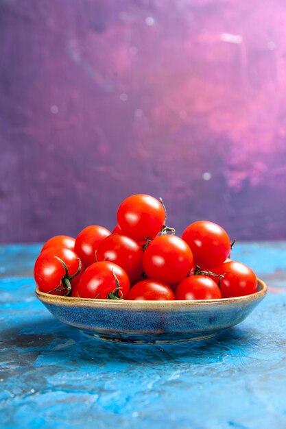 Vista frontale pomodori rossi freschi all'interno del piatto sul tavolo blu