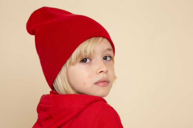 Vista frontale ragazzino carino in camicia rossa e cappello