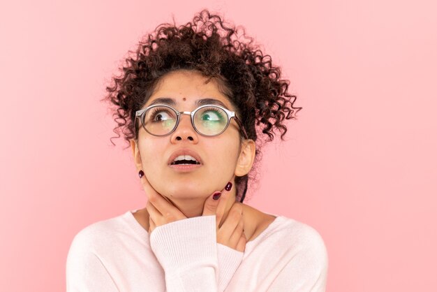 Vista frontale ravvicinata della giovane donna che pensa sul rosa