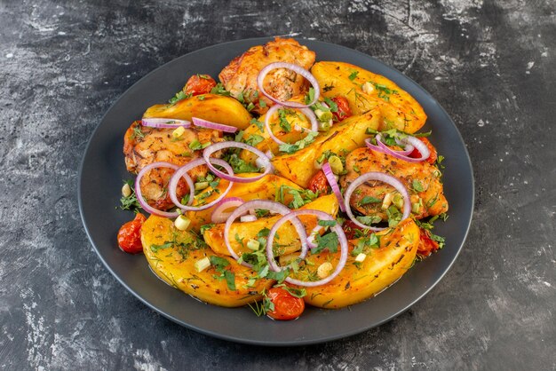 Vista frontale ravvicinata di una deliziosa cena con polli patate verdi in casseruola su un piatto grigio su sfondo di colore scuro con spazio libero