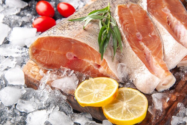 Vista frontale ravvicinata fette di pesce fresco con ghiaccio su sfondo grigio scuro ristorante cena pasto frutti di mare salute oceano cibo carne