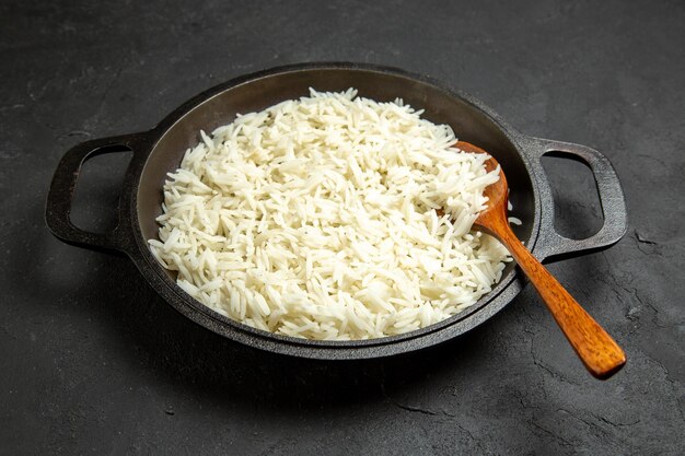 Vista frontale riso cotto all'interno della padella sulla superficie scura pasto cibo riso cena orientale