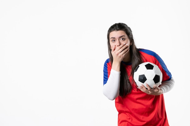 Vista frontale scioccata giovane donna in abiti sportivi con pallone da calcio