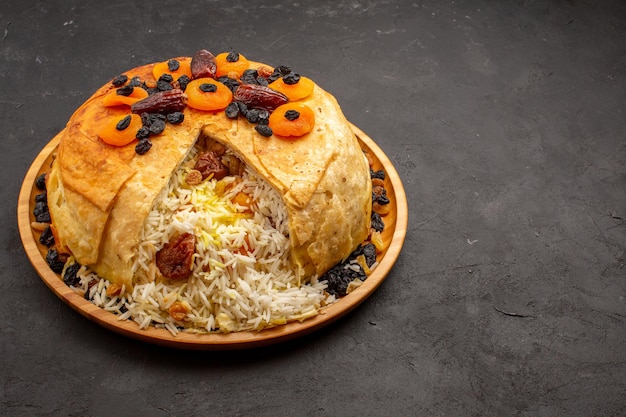 Vista frontale shakh plov delizioso pasto di riso cucinato all'interno di pasta rotonda con uvetta sullo spazio grigio