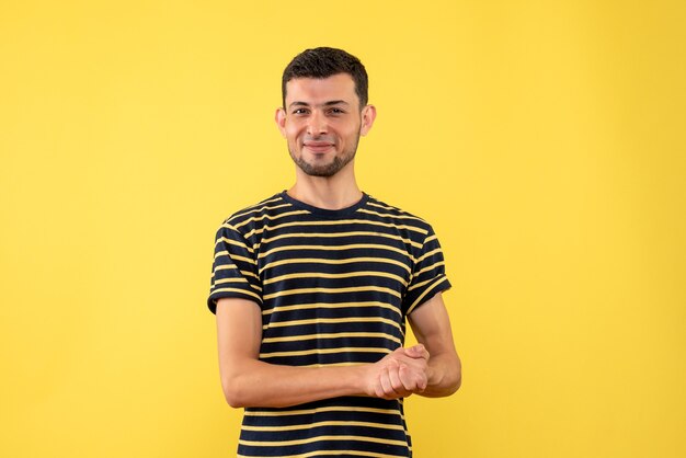 Vista frontale soddisfatto giovane uomo in bianco e nero a strisce t-shirt sfondo giallo isolato