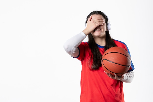 Vista frontale sorridente giovane femmina in abiti sportivi con basket