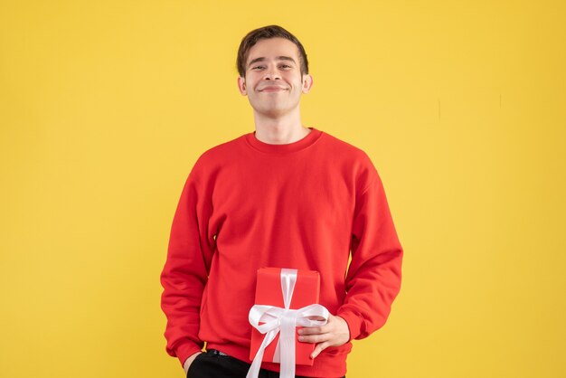 Vista frontale sorrise giovane uomo con maglione rosso in piedi sul giallo