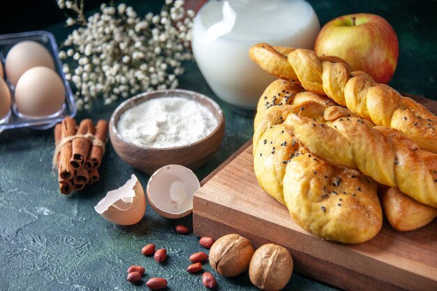 Vista frontale squisiti pasticcini con uova farina e latte su una parete scura pane cibo pasto colazione mattina latte uccello colore