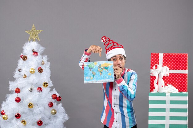 Vista frontale stupito uomo con molla a spirale santa cappello che punta il dito sulla mappa