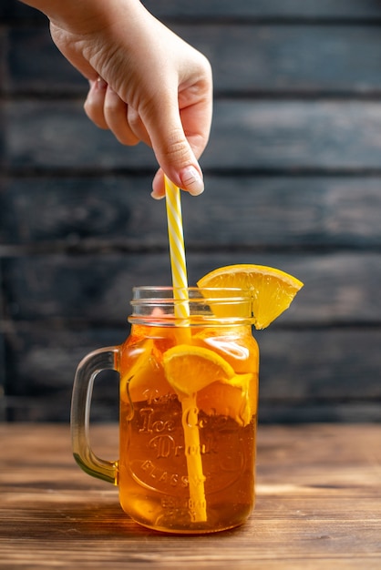 Vista frontale succo d'arancia fresco all'interno della lattina con paglia su drink cocktail di frutta con bar scuro