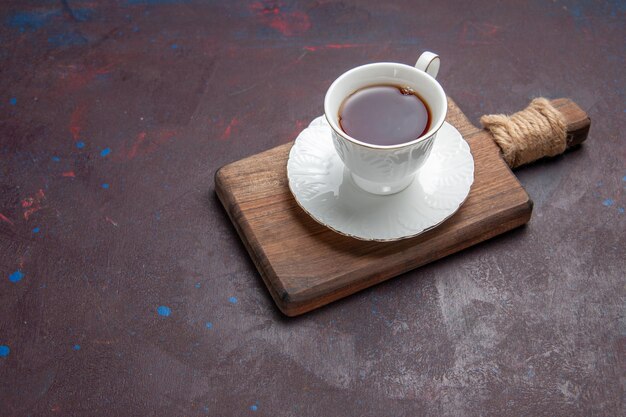 Vista frontale tazza di tè all'interno di una tazza di vetro con piatto sullo spazio buio