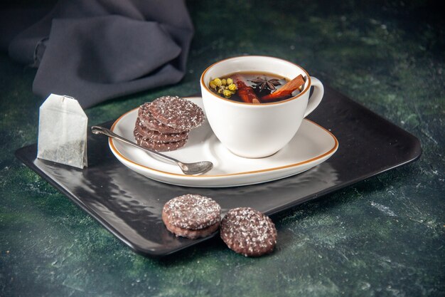 vista frontale tazza di tè con biscotti al cioccolato dolce nel piatto e vassoio sulla superficie scura cerimonia di vetro dolce colazione zucchero torta dessert colore