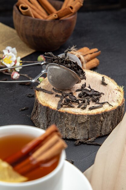 Vista frontale tazza di tè con cannella marrone su sfondo scuro pasto colore cerimonia colazione pranzo cibo al limone