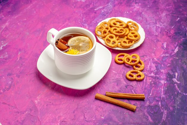 Vista frontale tazza di tè con cracker sul tavolo rosa color caramella al limone tè