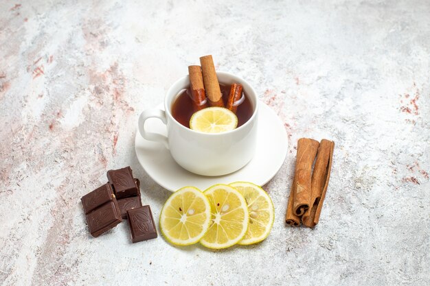 Vista frontale tazza di tè con fette di limone e cioccolato su uno spazio bianco