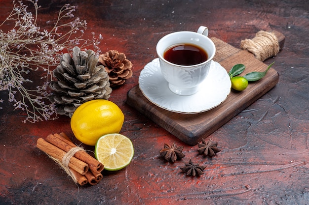 Vista frontale tazza di tè con limone e cannella su sfondo scuro