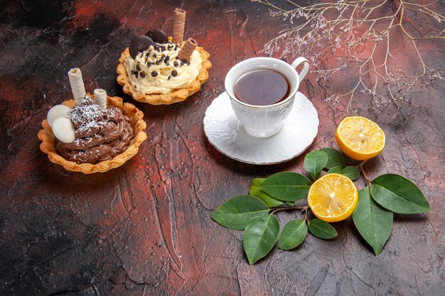 Vista frontale tazza di tè con piccola torta su sfondo scuro