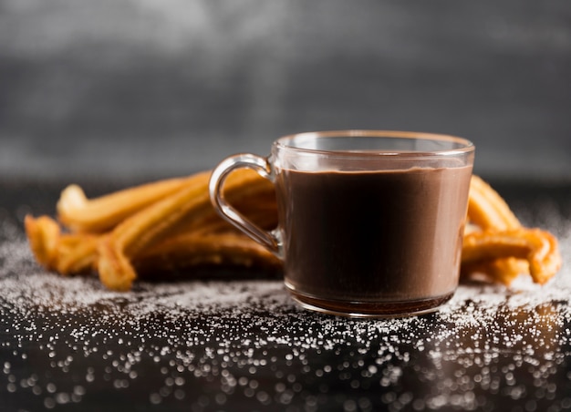 Vista frontale tazza trasparente di cioccolato fuso e churros