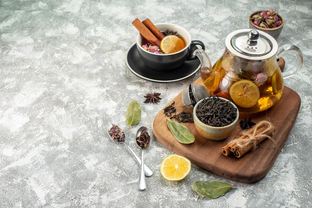 Vista frontale tè al limone in tazza e bollitore su sfondo bianco cerimonia dei fiori colore alimentare sapore mattutino colazione alla frutta