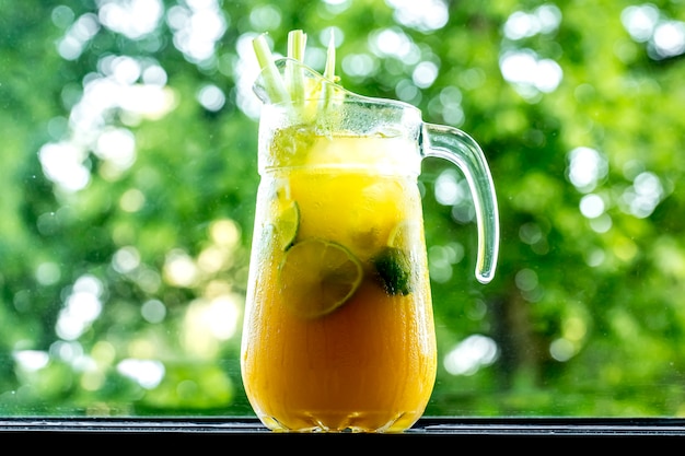 Vista frontale tonificante limonata in decanter con limone lime orange e sedano