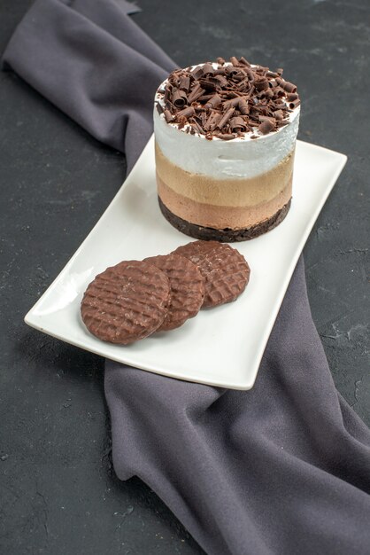 Vista frontale torta al cioccolato e biscotti su piatto rettangolare bianco scialle viola su oscurità