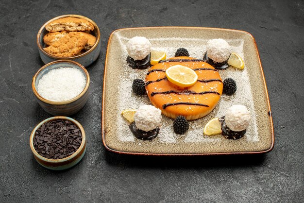 Vista frontale torta squisita dolce con caramelle al cocco su sfondo grigio scuro torta dolce biscotto