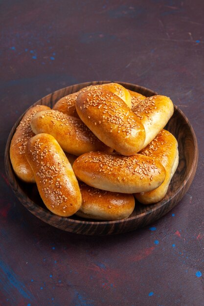 Vista frontale tortini dolci deliziosa pasta al forno per il tè in uno spazio buio