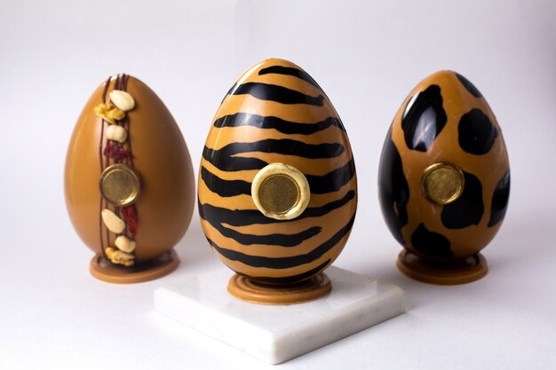 Vista frontale tre uova di cioccolato in oro e nero in oro tigre e leopardo colori sul cavalletto