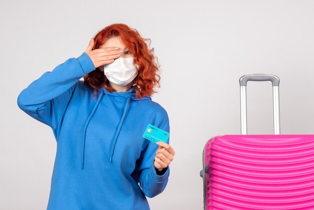 Vista frontale turista femminile in possesso di carta bancaria in maschera