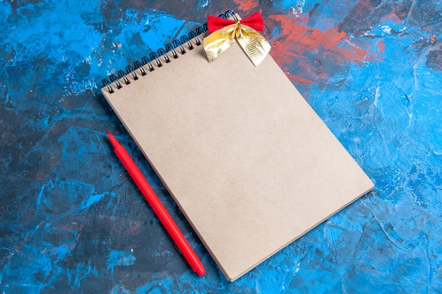 Vista frontale un blocco note con matita rossa fiocco su sfondo blu con spazio copia