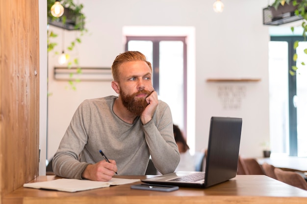 Vista frontale uomo barbuto prendere appunti al lavoro