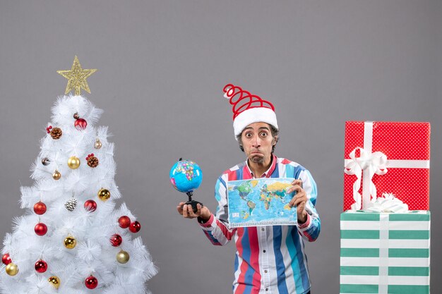 Vista frontale uomo sorpreso con molla a spirale santa hat holding mappamondo e globo