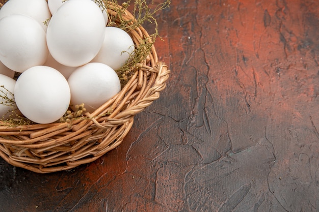 Vista frontale uova di gallina fresche all'interno del cesto sulla superficie scura