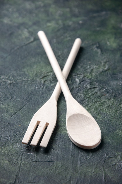 Vista frontale utensili in legno su uno sfondo scuro cibo coltello da cucina forchetta da cucina in plastica cucchiaio posate foto