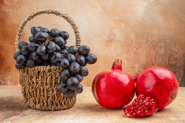 Vista frontale uva nera fresca con melograni sullo sfondo chiaro frutta matura vino dolce foto