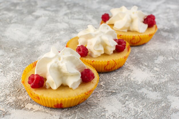 Vista frontale vicino torte con crema buonissimo al forno progettato con lampone sulla scrivania grigia