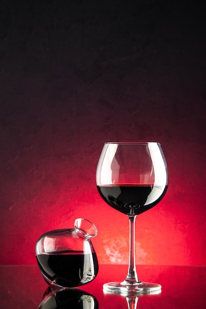 Vista frontale vino rosso all'interno della fiaschetta e bicchiere di vino su sfondo rosa colore nero uva foto bevande alcolici bar