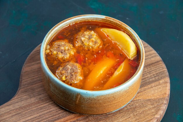 Vista frontale zuppa di polpette di carne con patate all'interno del piatto rotondo sul muro blu scuro cibo zuppa di carne piatto cena verdura