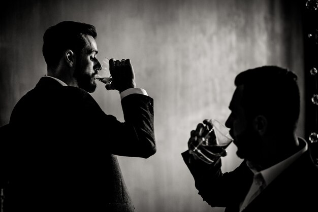 Vista in bianco e nero di due uomini che bevono bevande alcoliche al chiuso