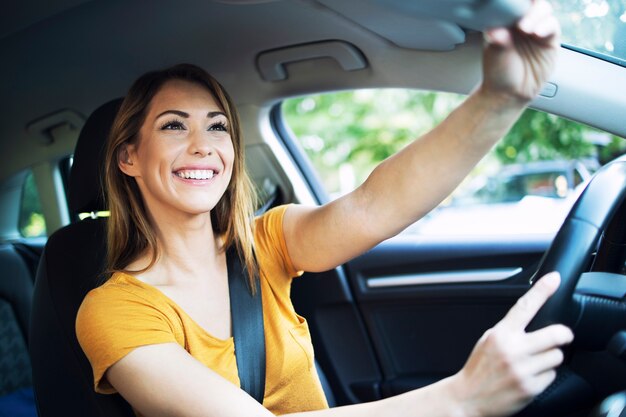 Vista interna dell'automobile del driver femminile della donna che registra gli specchi prima di guidare un'auto