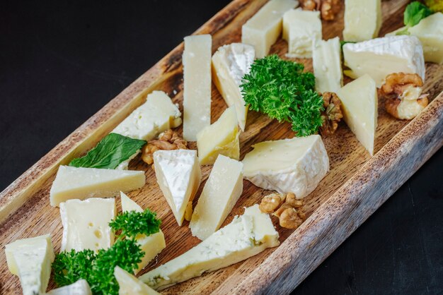 Vista laterale affettato formaggio roquefort con erbe e noci su un piatto di legno